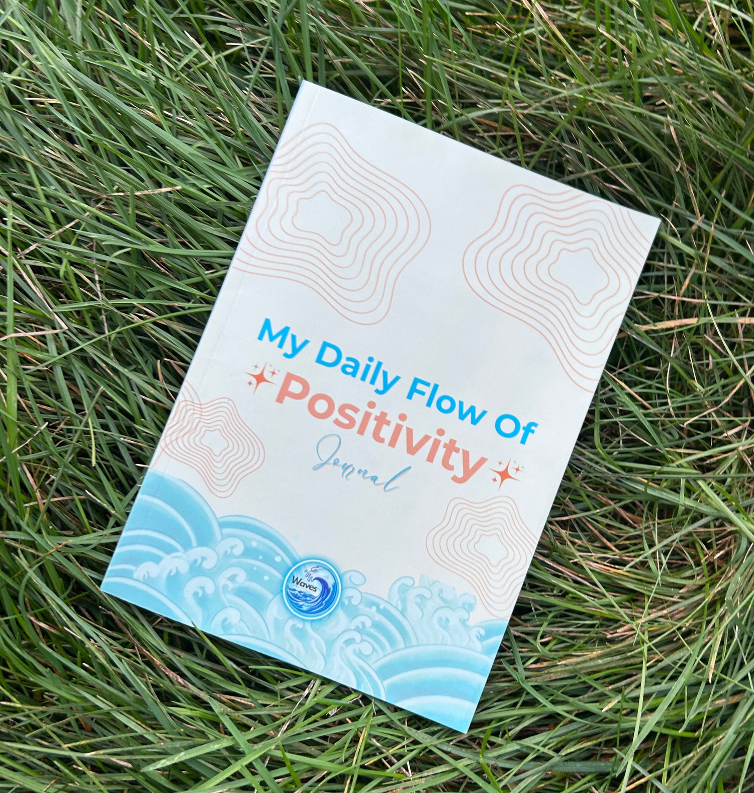 Book titled 'My Daily Flow of Positivity' on grass