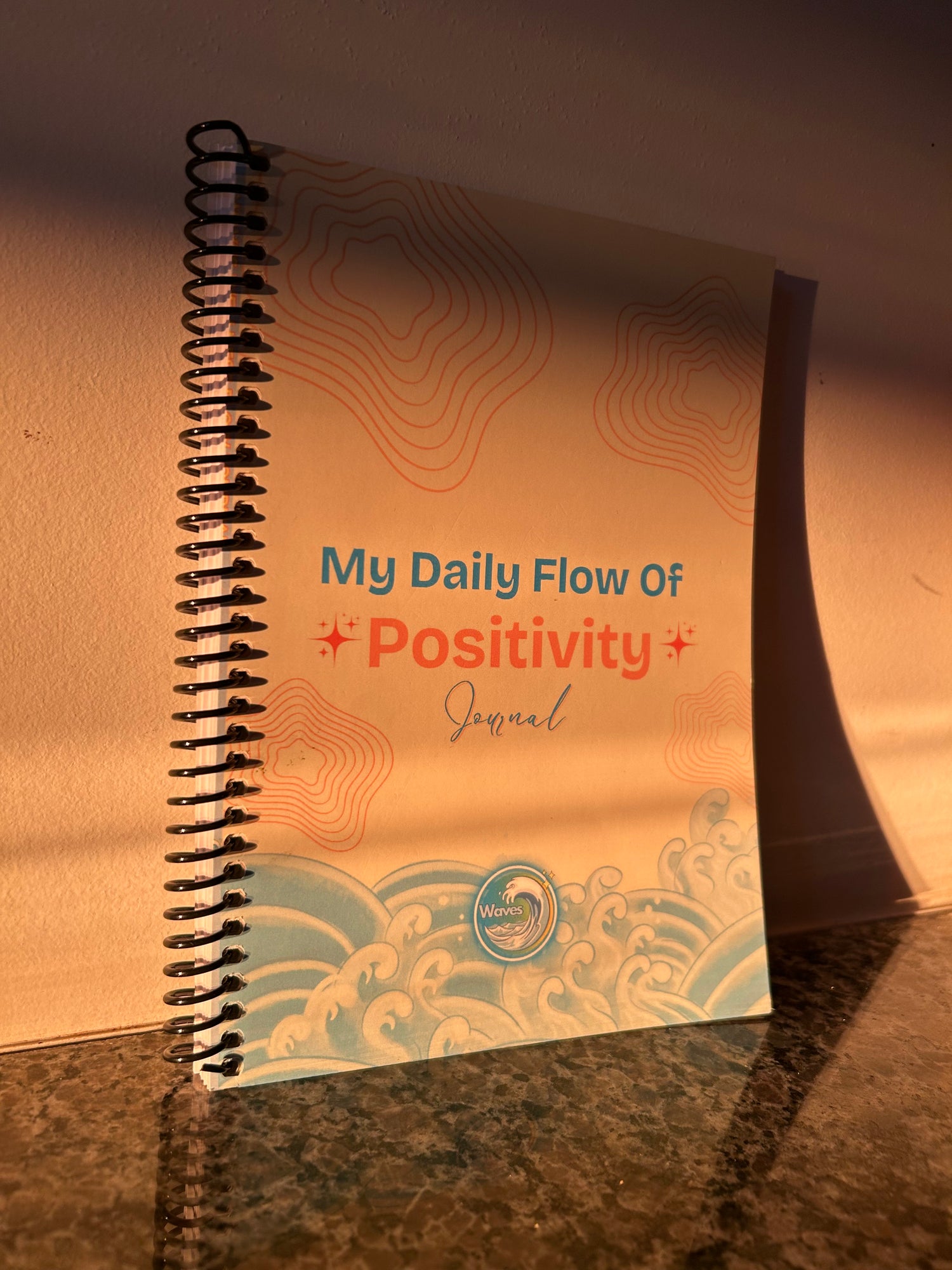 Notebook titled 'My Daily Flow of Positivity Journal' on a reflective surface. Ships US/UK/Canada.
