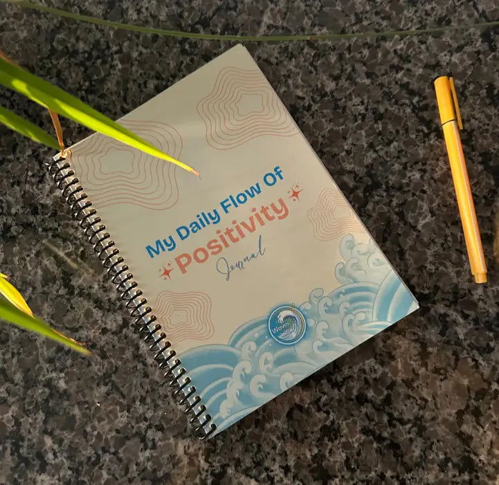guided wellness Journal titled 'My Daily Flow of Positivity' by waves wellness with a pen on a textured marble surface